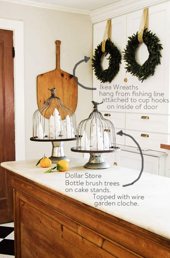 White bottle brush trees on cake stands for Christmas decorating on an antique marble topped candy counter.