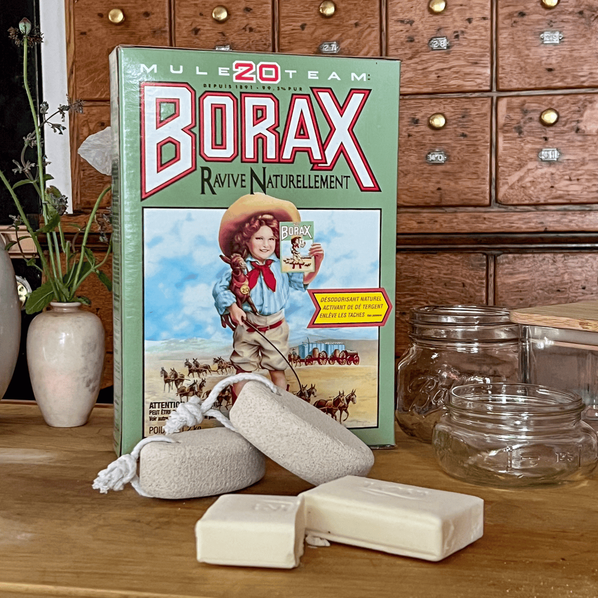 Borax, pumice stones, mason jars and soap laid out on wood cutting board for making hand scrub.