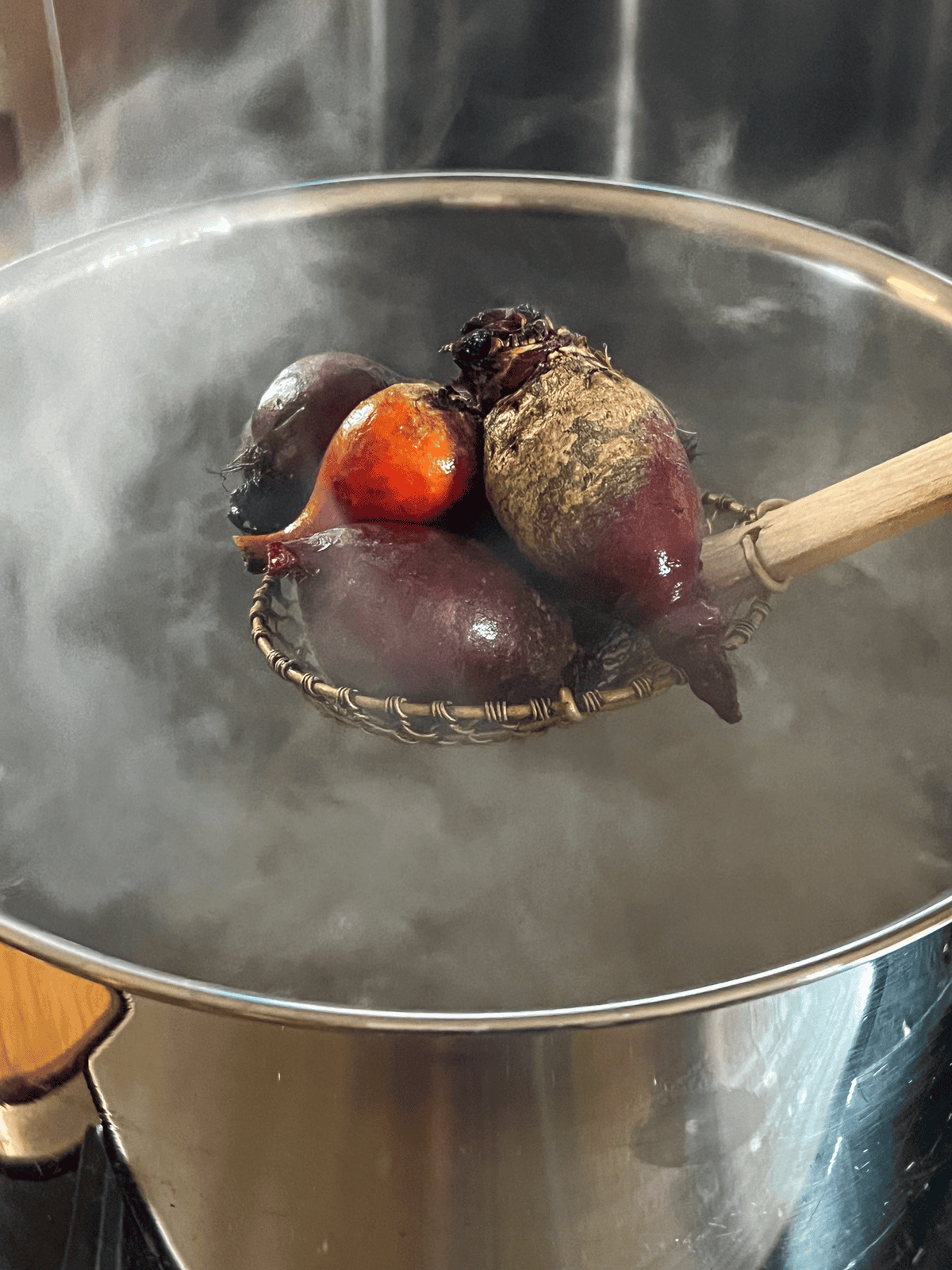 Removing beets from boiling water with a spider.