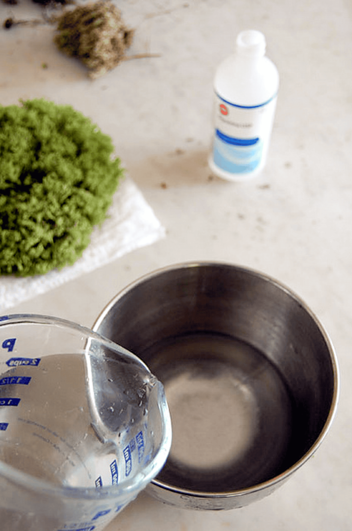 Hot water being poured from pyrex measuring cup into stainless steel bowl.