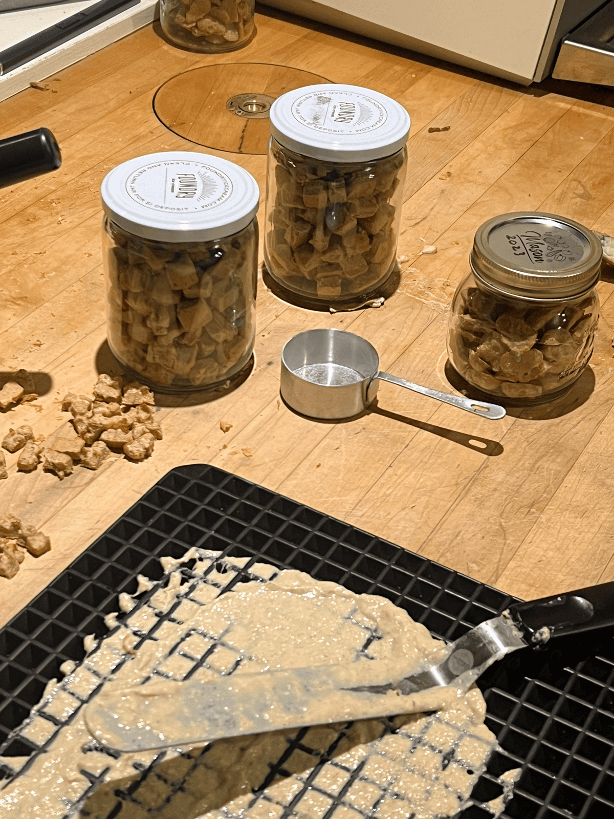 Runny meat batter poured into a silicone dog treat mold on a wood countertop.