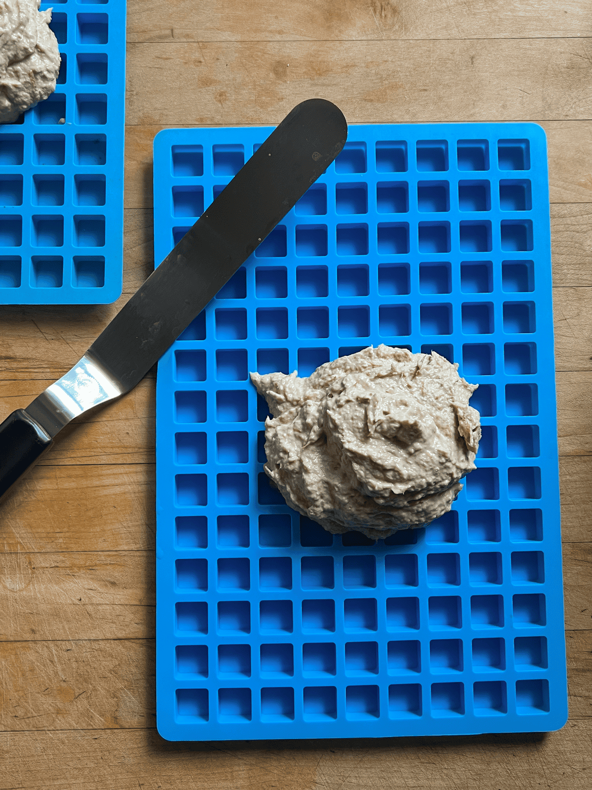 Homemade dog treat batter blobbed onto a blue silicone treat mold.