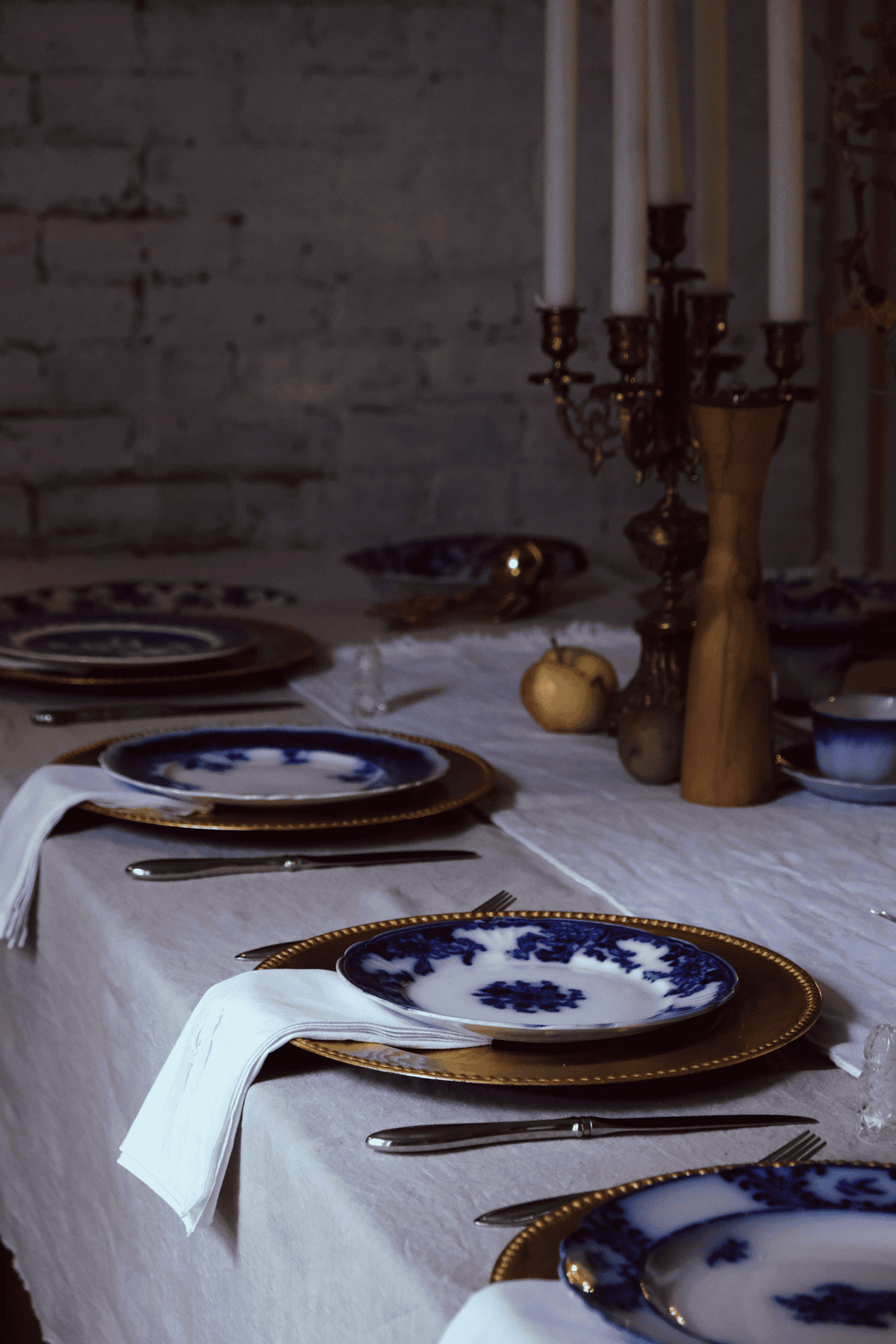 Moody still life of flow blue dishes on gold chargers.