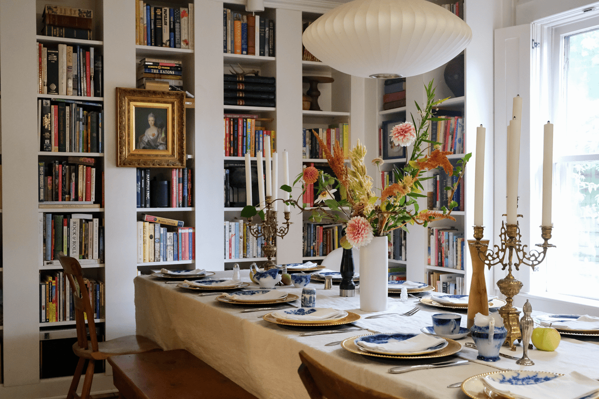 Library/Dining Room with table set with linen, flow blue, and brass candelabras.